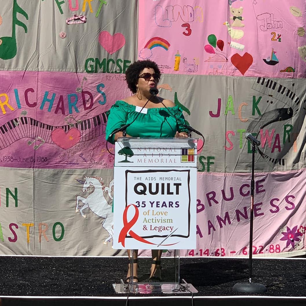 Dafina Ward speaking in front of AIDS Quilt